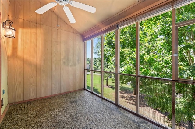 unfurnished sunroom featuring baseboards, wood walls, and lofted ceiling