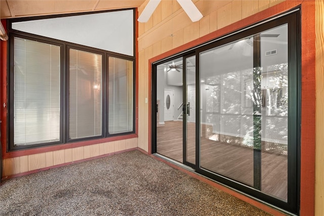 exterior space featuring ceiling fan, wood walls, and carpet