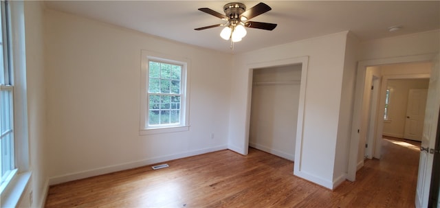 unfurnished bedroom with ceiling fan, a closet, and hardwood / wood-style flooring