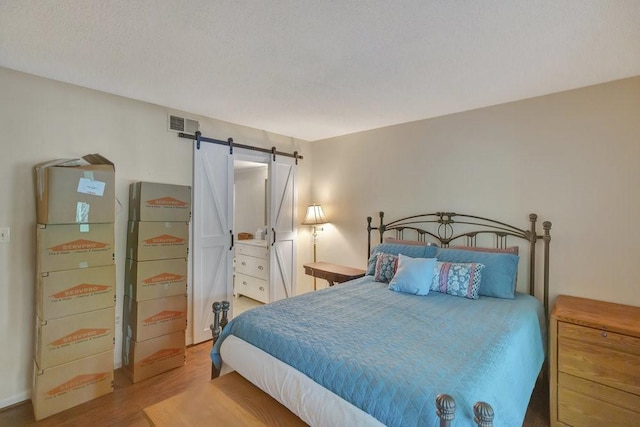 bedroom with hardwood / wood-style flooring, a barn door, and a textured ceiling