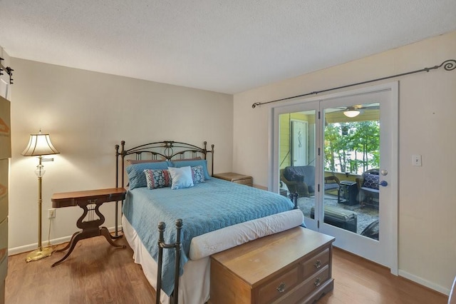 bedroom with hardwood / wood-style floors, access to outside, and a textured ceiling