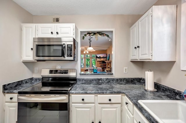 kitchen with stainless steel appliances, sink, white cabinets, and a textured ceiling