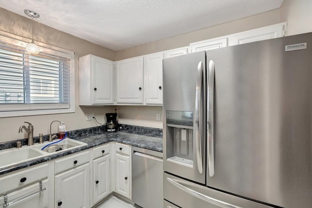 kitchen featuring sink, white cabinets, dark stone counters, stainless steel appliances, and a textured ceiling