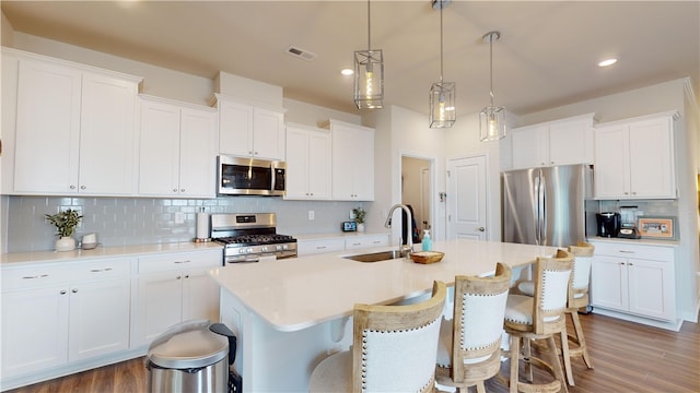 kitchen with hanging light fixtures, sink, white cabinetry, stainless steel appliances, and dark hardwood / wood-style flooring