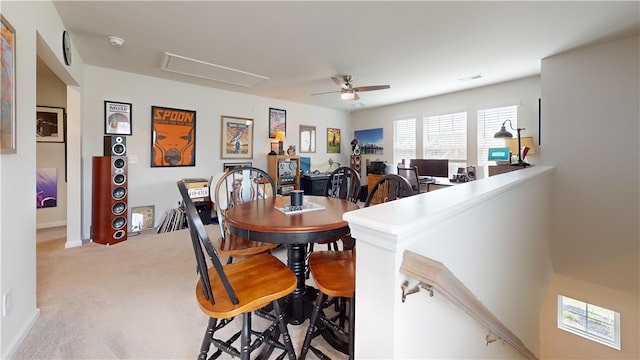 dining space with ceiling fan and light colored carpet