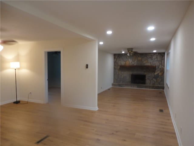 unfurnished living room featuring light wood-type flooring and a stone fireplace