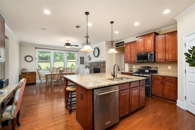 kitchen with ceiling fan, sink, a center island with sink, stainless steel appliances, and dark hardwood / wood-style flooring