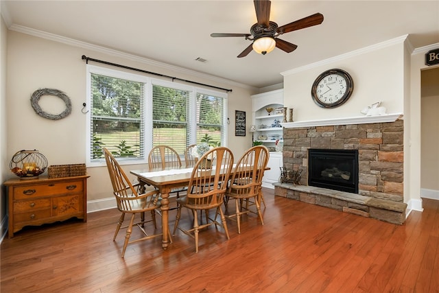 dining room with a stone fireplace, ceiling fan, and hardwood / wood-style flooring