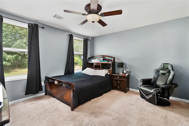 bedroom featuring light carpet, ceiling fan, and multiple windows