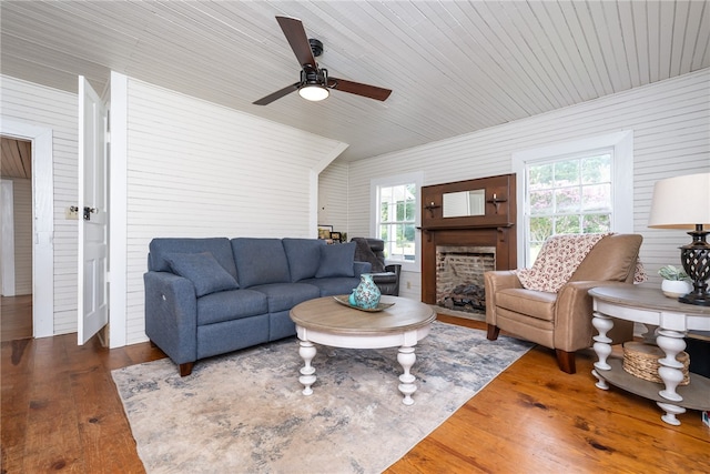 living room featuring ceiling fan, wood walls, and dark hardwood / wood-style flooring