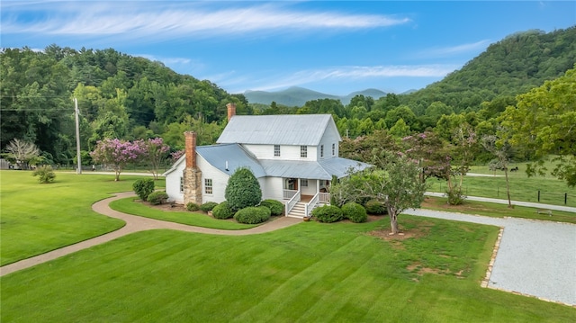 view of front of home featuring a mountain view, a front lawn, and covered porch