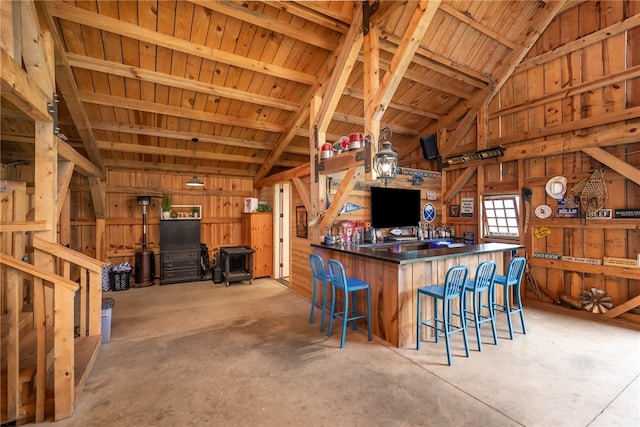 kitchen with wooden ceiling, vaulted ceiling with beams, kitchen peninsula, and wood walls