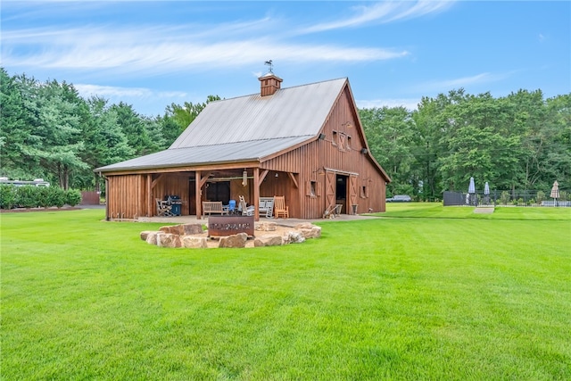 back of house with a lawn, an outbuilding, and a fire pit