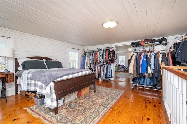 bedroom featuring multiple windows, wooden ceiling, wooden walls, and hardwood / wood-style flooring