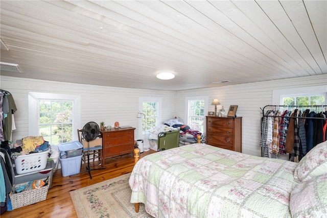 bedroom featuring multiple windows, light hardwood / wood-style floors, and wooden ceiling