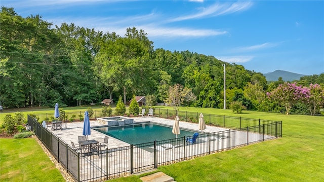 view of swimming pool featuring a mountain view, a patio, a lawn, and an in ground hot tub