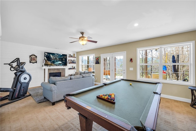 game room featuring pool table, a tiled fireplace, ceiling fan, and light colored carpet