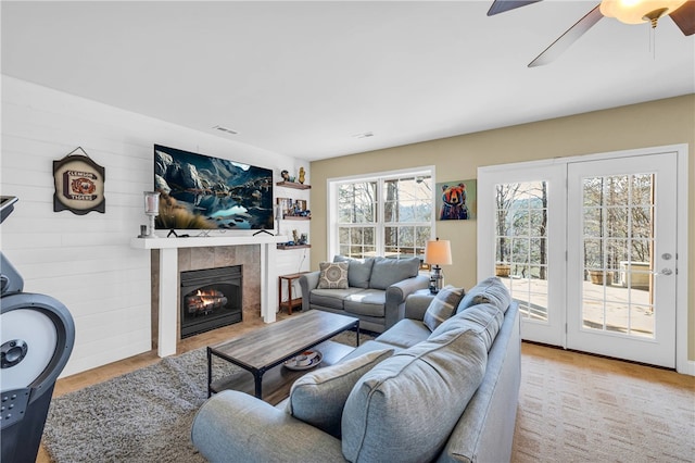 living room featuring light wood-type flooring, ceiling fan, and a fireplace