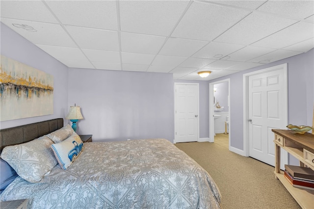 bedroom with ensuite bath, carpet flooring, and a paneled ceiling