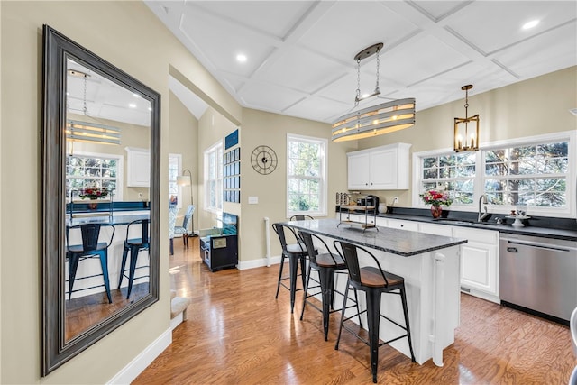 kitchen with stainless steel dishwasher, white cabinetry, a center island, and decorative light fixtures