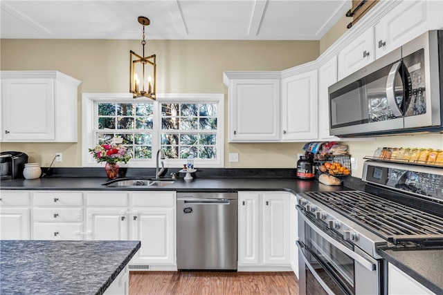 kitchen featuring hanging light fixtures, sink, light hardwood / wood-style flooring, white cabinetry, and stainless steel appliances