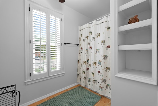 bathroom with hardwood / wood-style flooring, a healthy amount of sunlight, and curtained shower