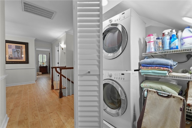 laundry room with stacked washer and dryer, light hardwood / wood-style floors, and ornamental molding