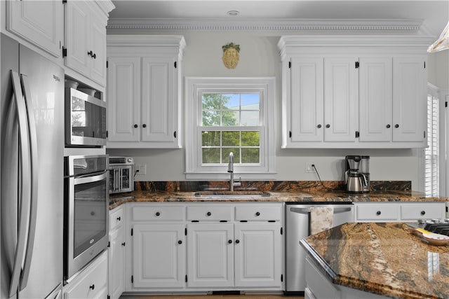 kitchen with dark stone counters, white cabinetry, sink, and stainless steel appliances