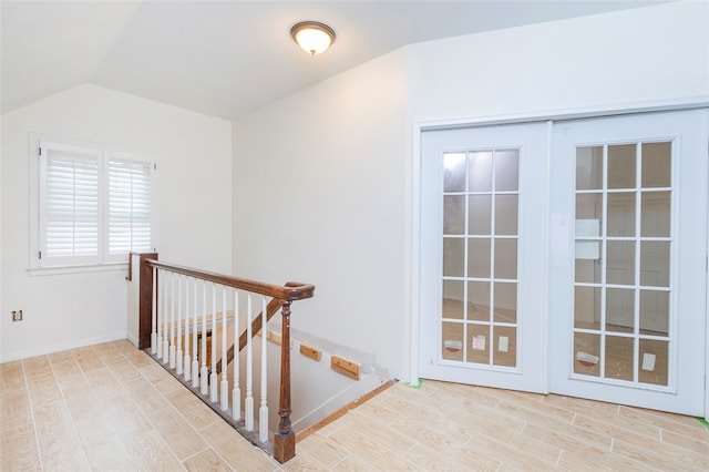 stairway with french doors, vaulted ceiling, and hardwood / wood-style flooring