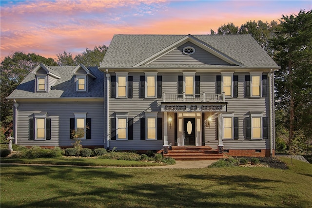 colonial inspired home featuring a balcony and a lawn