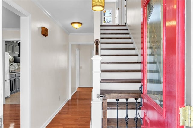 stairway featuring hardwood / wood-style floors, sink, and crown molding