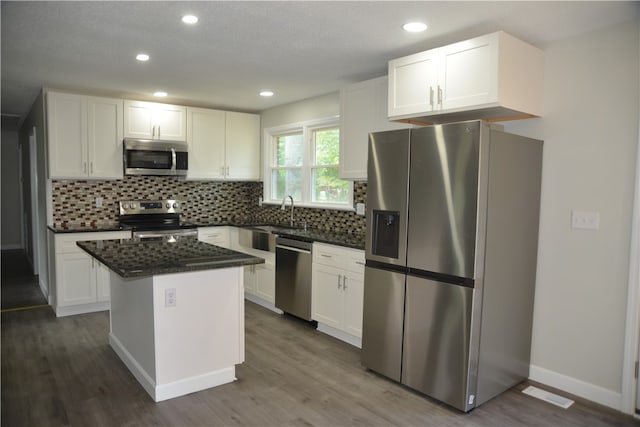 kitchen featuring stainless steel appliances, white cabinetry, a kitchen island, and dark hardwood / wood-style flooring