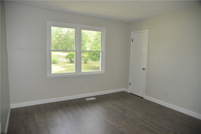 spare room with dark wood-style floors, baseboards, and visible vents