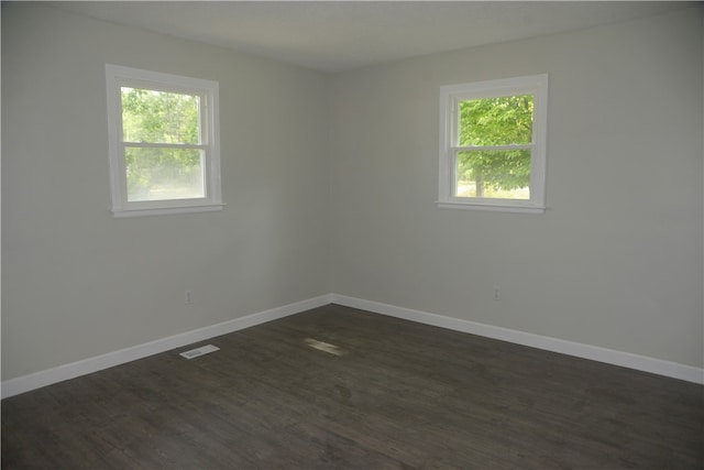 spare room with plenty of natural light and dark hardwood / wood-style floors