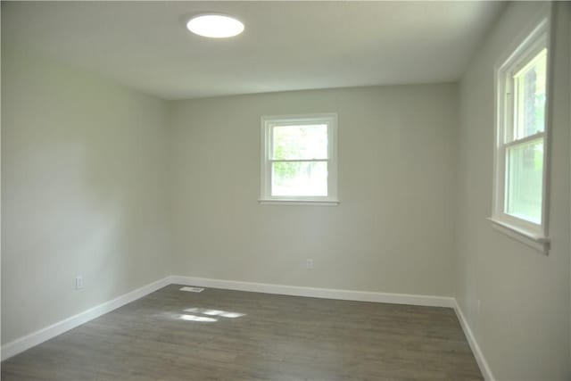 unfurnished room featuring dark wood-style flooring, baseboards, and visible vents