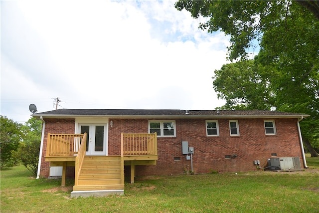 rear view of property with french doors, a deck, a lawn, and central AC