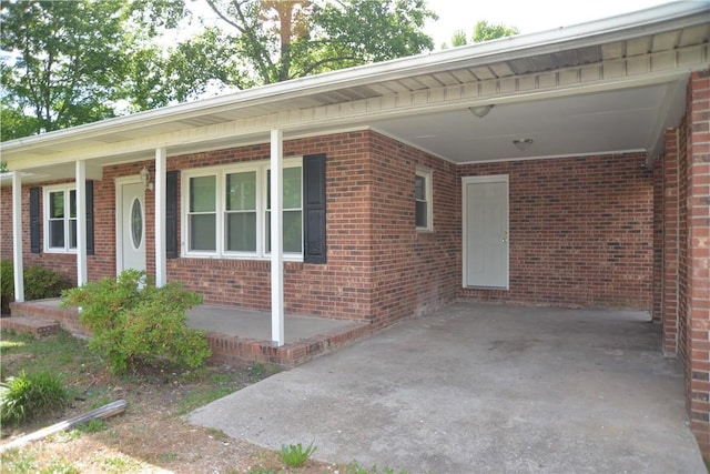exterior space featuring an attached carport, brick siding, and covered porch