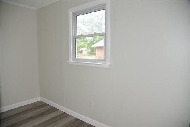 spare room featuring baseboards, crown molding, and wood finished floors