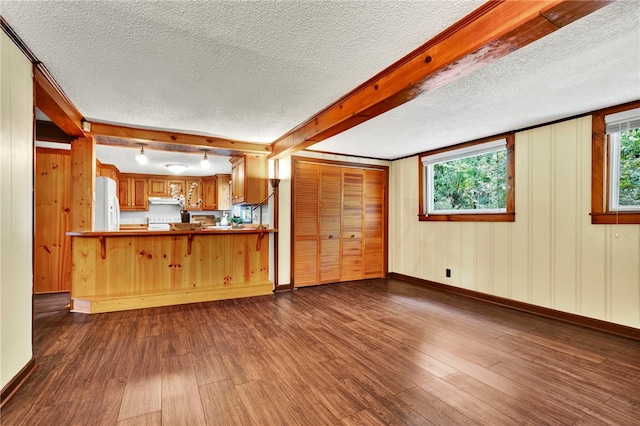 kitchen with white refrigerator, a textured ceiling, dark hardwood / wood-style floors, a breakfast bar area, and kitchen peninsula