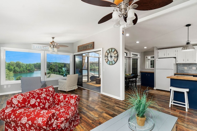 living room featuring lofted ceiling, a water view, ceiling fan, and dark wood-type flooring