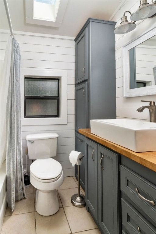 full bathroom featuring vanity, toilet, a skylight, and tile patterned floors