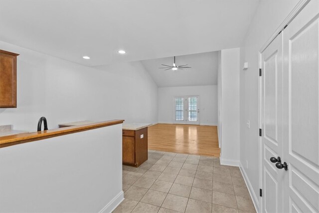 kitchen featuring vaulted ceiling, ceiling fan, light tile patterned floors, and french doors