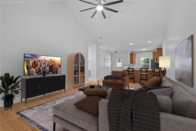 living room with ceiling fan, light hardwood / wood-style floors, and high vaulted ceiling