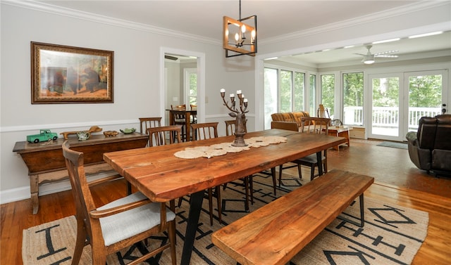 dining area with crown molding, ceiling fan with notable chandelier, and dark hardwood / wood-style floors