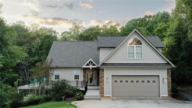 view of front of property with concrete driveway, a shingled roof, and stone siding