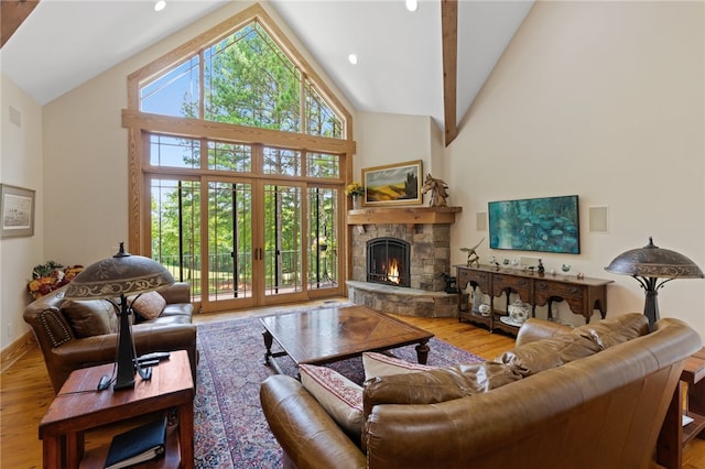 living room featuring a stone fireplace, light hardwood / wood-style floors, and high vaulted ceiling