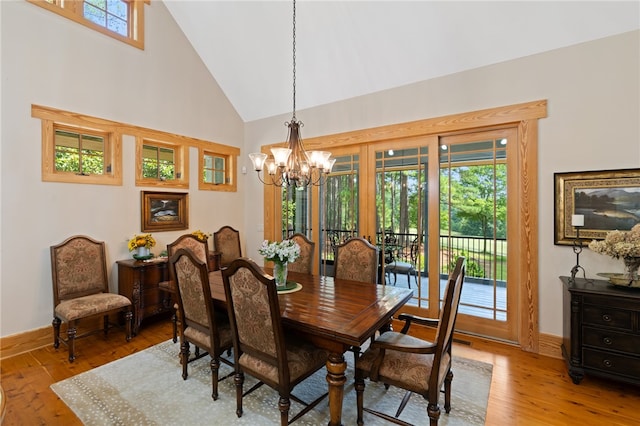 dining room featuring light wood-type flooring, an inviting chandelier, and high vaulted ceiling