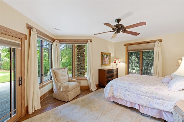 bedroom with wood-type flooring, access to outside, and ceiling fan