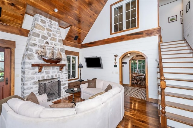 living room featuring wood ceiling, wood walls, dark hardwood / wood-style flooring, a fireplace, and high vaulted ceiling