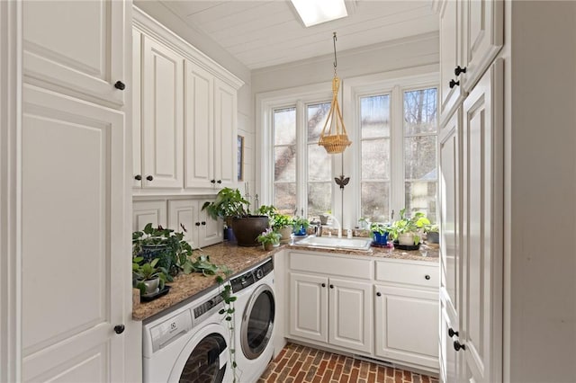 clothes washing area featuring sink, washing machine and clothes dryer, and cabinets